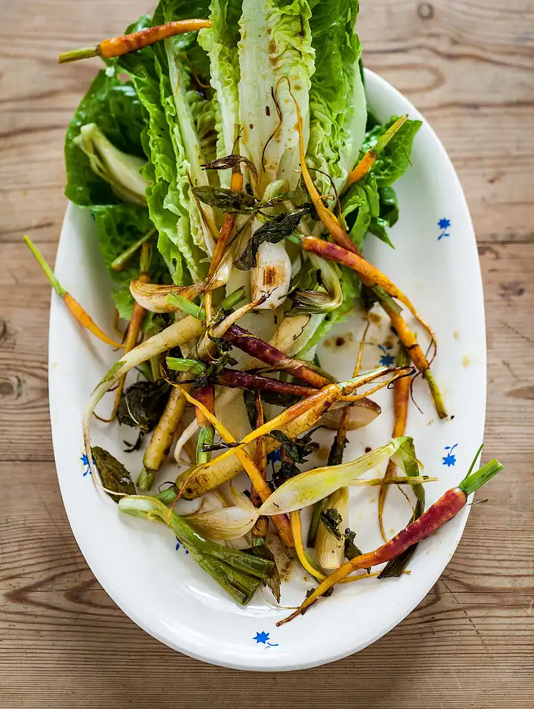 Bagte nye gulerødder og løg med mynte, løvstikke og sprød romainesalat