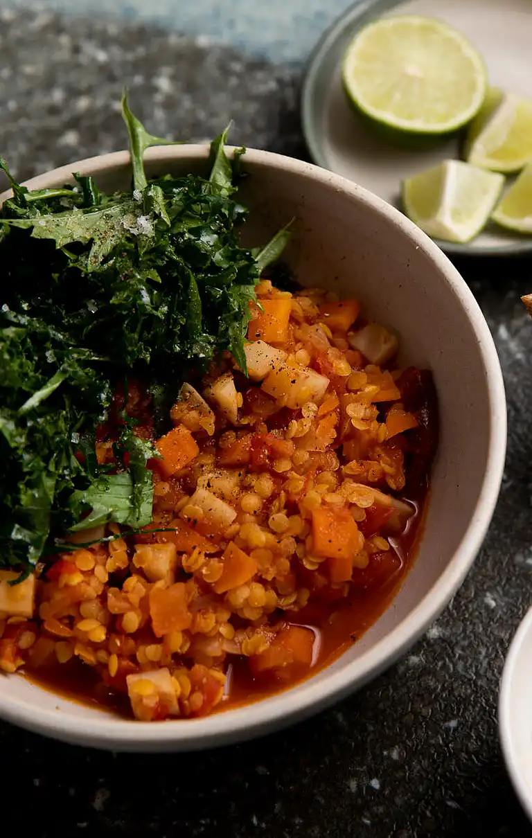 Dahl af røde linser med kartofler, tomater og grønkål samt nøddedrys