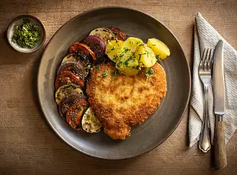 Nakkekoteletter som schnitzler med råstegte kartofler og tomatsalat