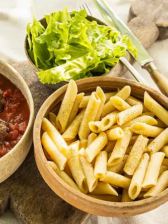 Pastapenne med sauce af friske tomater og skinkekød samt grøn salat