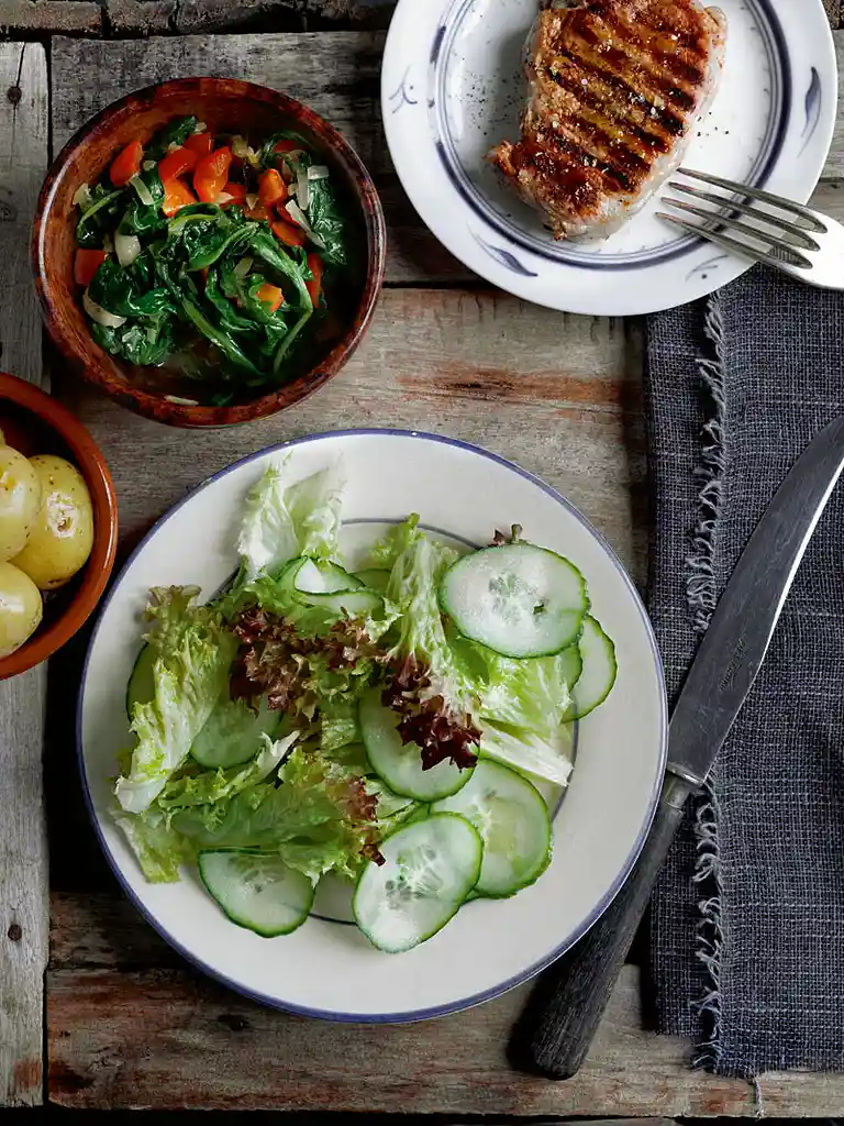 Svinekoteletter og spinat med nye kartofler og salat med saltede agurker